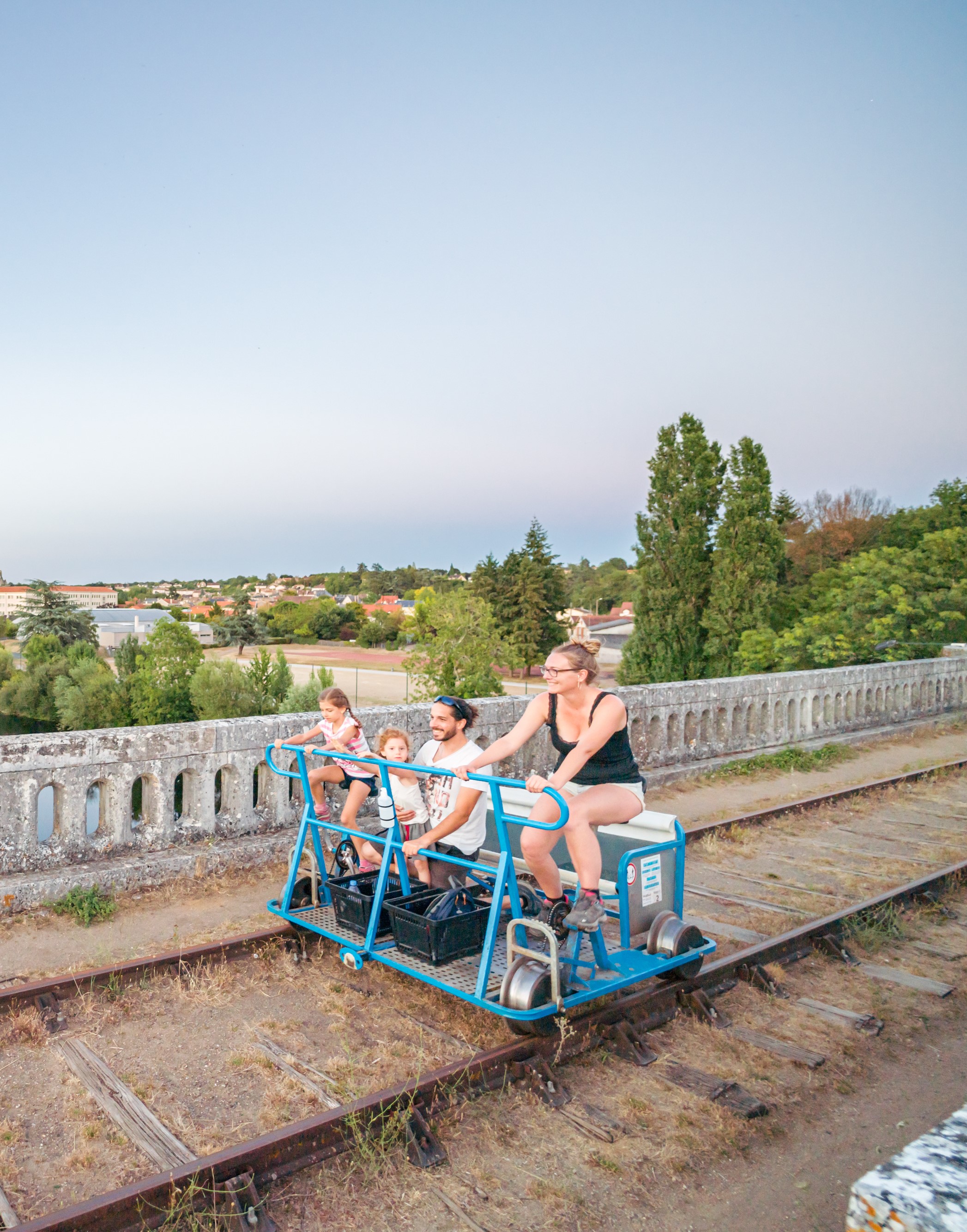 Une famille profitant d'une balade en vélorail avec une vue imprenable sur la ville historique de Chauvigny, entre nature et patrimoine